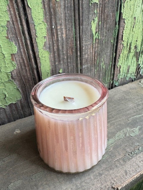 Candle in a ribbed container on a rustic wooden surface